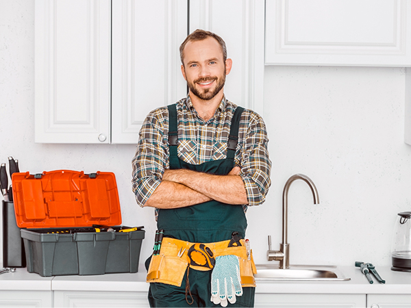 Plumbing technician in green overalls getting ready to work.