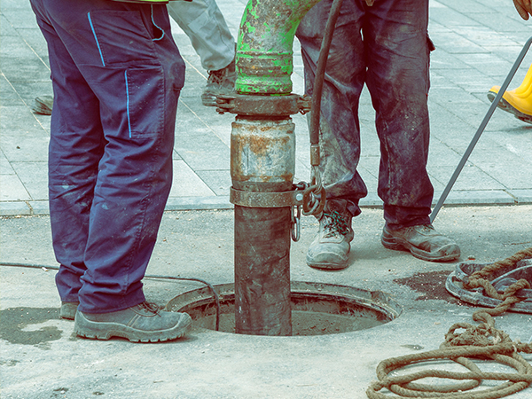 Plumbing technician in green overalls getting ready to work.